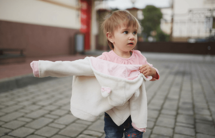 young child putting on cardigan back to front