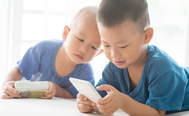 2 young children looking at phone screens