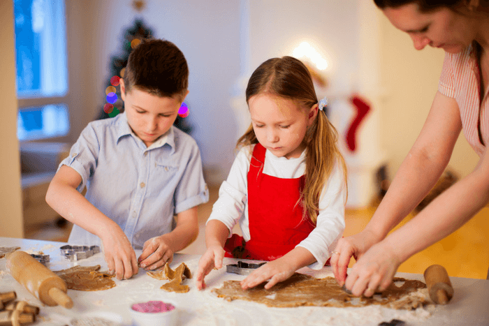 two kids making Christmas cookies with parent
