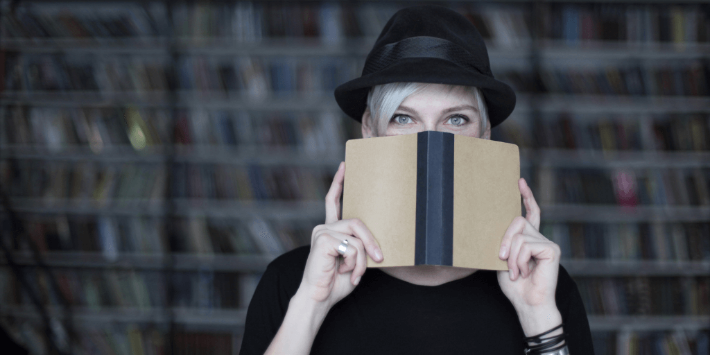 woman holding book in front of face