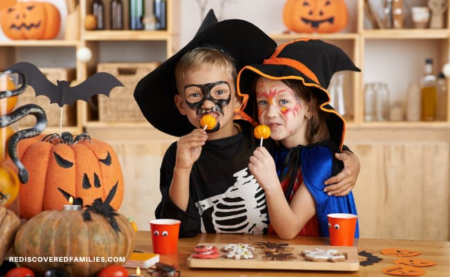 two kids dressed in Halloween costumes eating fall snacks