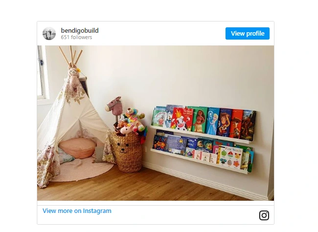 small teepee with cushions next to small book shelf