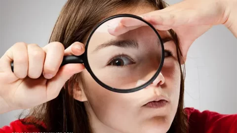 child looking through magnifying glass with one eye enlarged