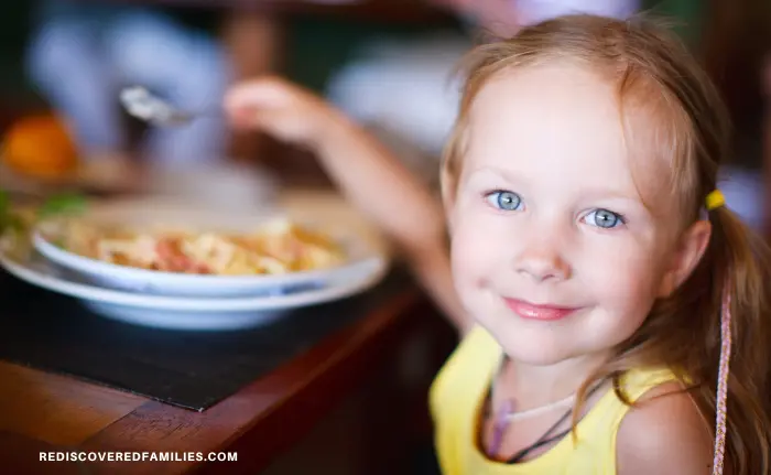 smiling girl with her spoon over a bowl of food