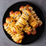 a close up of a plate of mummy hot dogs