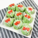 a plate of Grinch truffle balls displayed on a striped towel