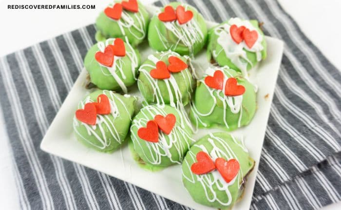 a plate of Grinch truffle balls displayed on a striped towel