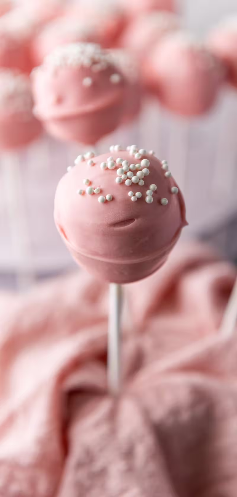 pink cake pops displayed with a pink cloth