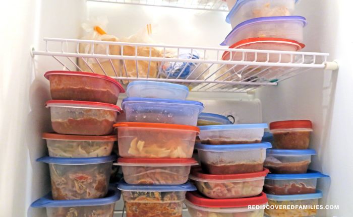 A freezer stacked with plastic containers of freezer meals