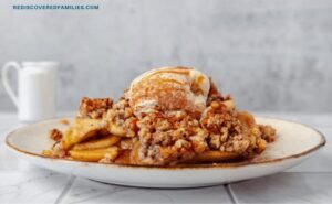 A plated serving of warm apple crisp topped with vanilla ice cream and drizzled with caramel.
