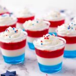 Close-up of colorful layered 4th of July Jello shots in clear cups, ready to serve at a party.