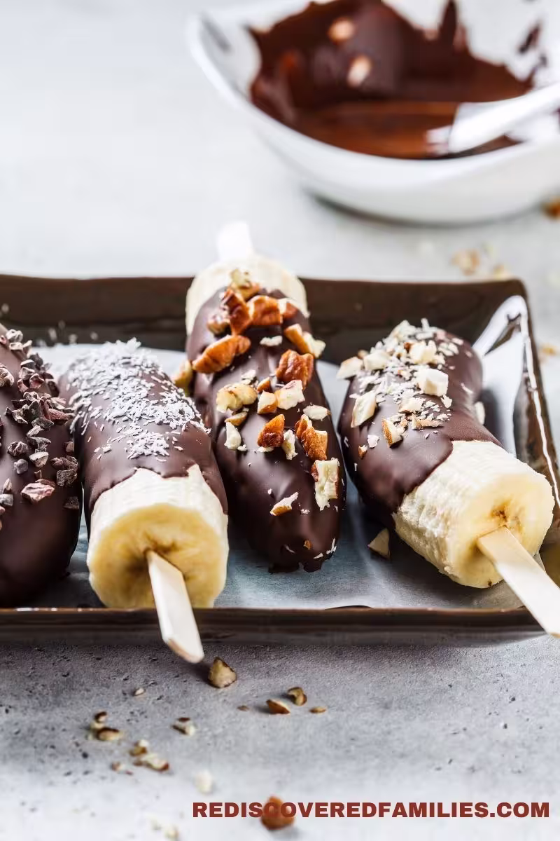 Chocolate-covered bananas topped with different toppings on a serving tray.