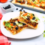 close up of two pieces of taco pizza on a plate