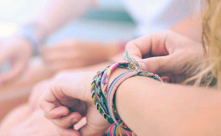 child's arms with a variety of yarn bracelets