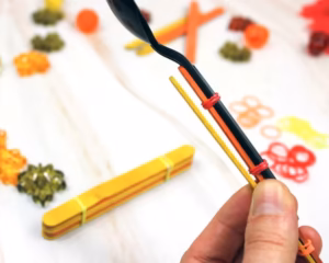 attaching the second popsicle stick to the spoon