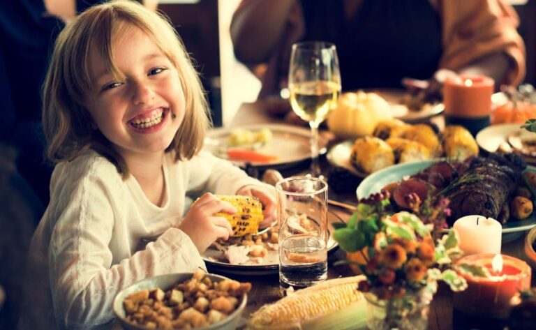 young girl laughs at a Thanksgiving table