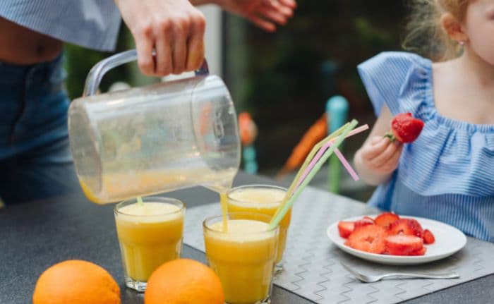 parent pours orange smoothies as an after school snack